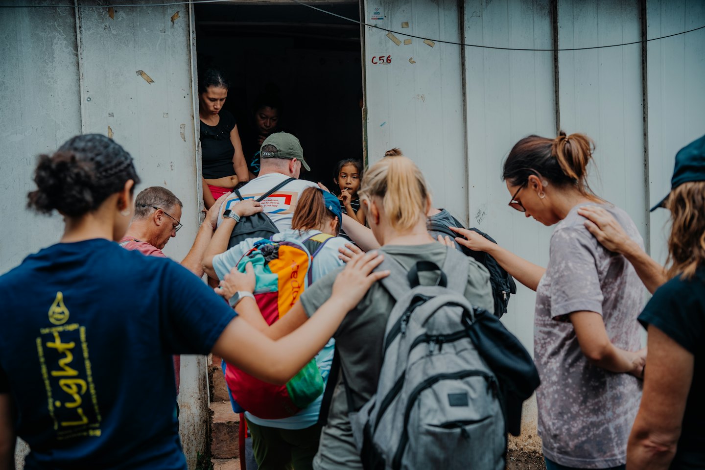 Volunteers huddle together near a doorway, with people inside a building.